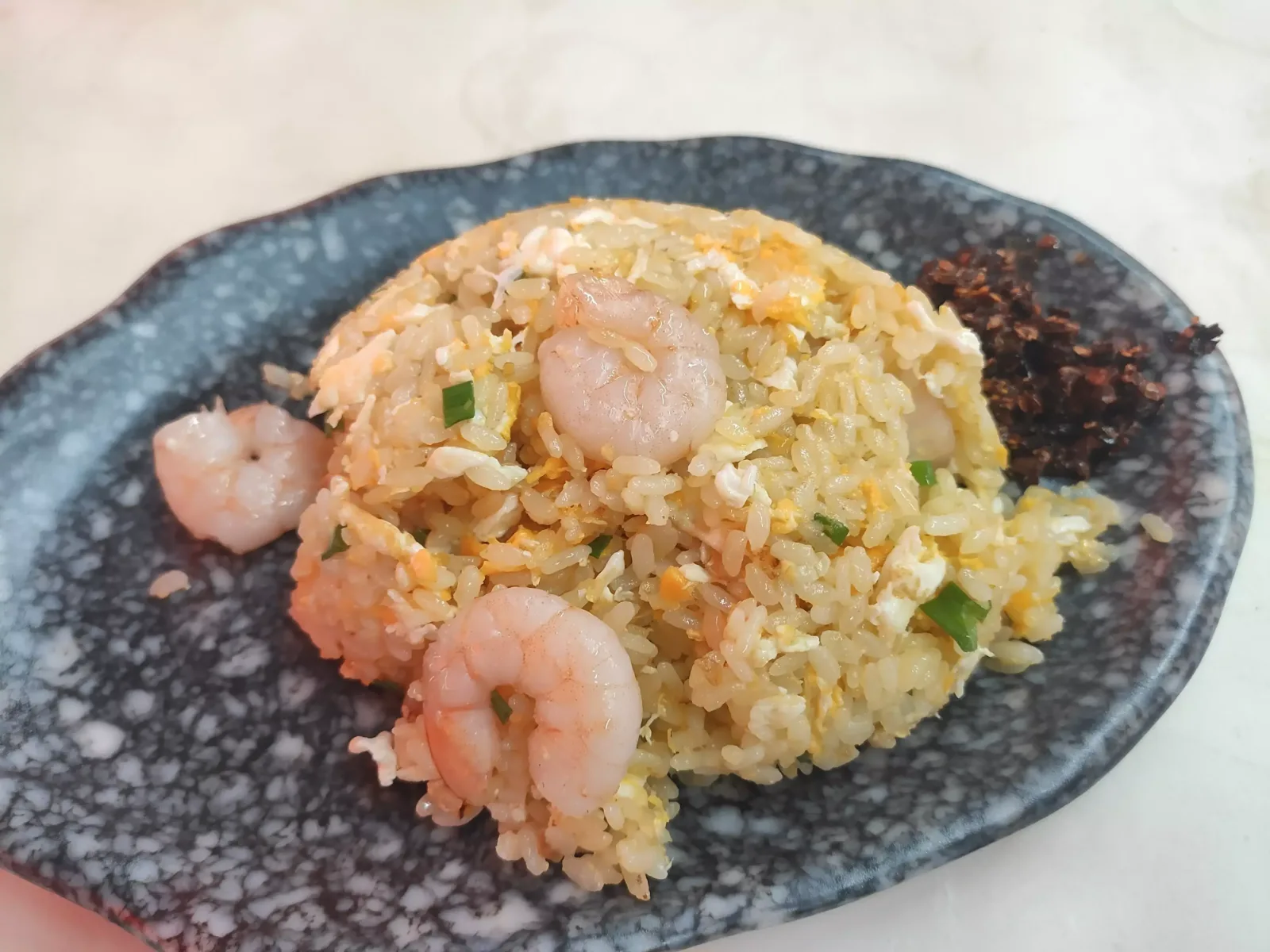 Egg fried rice with shrimp and a spoon of house chilli on the table